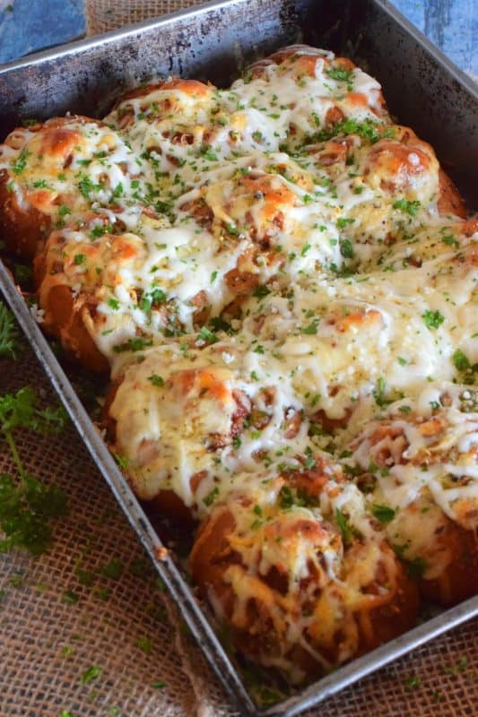 Garlic Bread Meatball Bombs are hollowed out dinner rolls which have been liberally smeared with homemade garlic butter. Each roll is stuffed with a meatball and sauce, then topped with cheese. Baked to a bubbling, gooey perfection, these bombs are the bomb! #meatballs #sliders #dinnerrollrecipes #bombs #meatballrecipes #familyrecipes #garlicbread