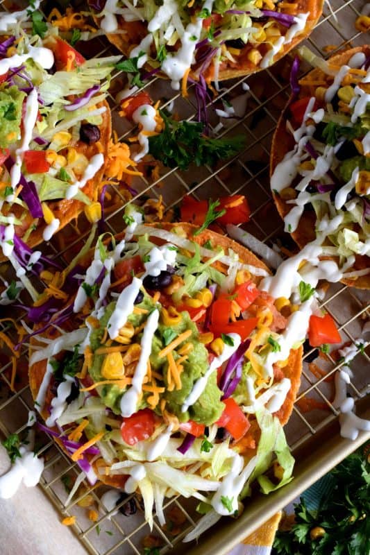Bean and Cheese Tostadas are piled high with fresh veggies and topped with guacamole and sour cream. They're like an unrolled burrito with the crunch of a taco. Try eating just one! #tostadas #Mexican #recipes #vegetarian