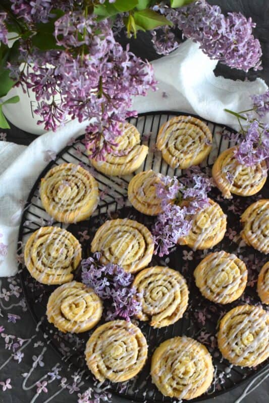 Sweet Lilac Bloom Rolls are made with a light, buttery, biscuit-like dough and rolled tightly with sugar and lilac petals. The sugar melts and begins to caramelize, while the petals infuse and permeate the rolls with a fresh fragrance and a mild lemony flavour. Drizzled with a lilac syrup icing, these are absolutely delicious and gorgeous too! #lilac #rolls #breakfast #brunch #frosting #iced #blooms #edibleflowers