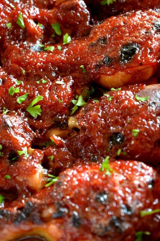 In this Charred Chipotle Chicken recipe, inexpensive drumsticks are baked with onion and then topped with a thick, sweet sauce consisting of chipotle peppers in adobo sauce, vinegar, brown sugar, and more.  This is certainly an easily family pleasing main! #bakedchicken #drumsticks #spicychicken #chipotle #adobosauce #saucy