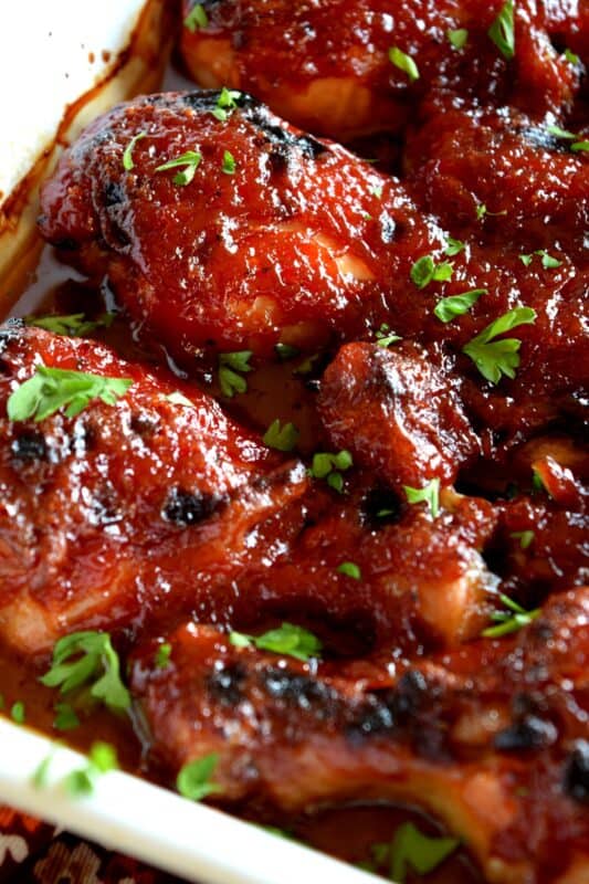 In this Charred Chipotle Chicken recipe, inexpensive drumsticks are baked with onion and then topped with a thick, sweet sauce consisting of chipotle peppers in adobo sauce, vinegar, brown sugar, and more.  This is certainly an easily family pleasing main! #bakedchicken #drumsticks #spicychicken #chipotle #adobosauce #saucy