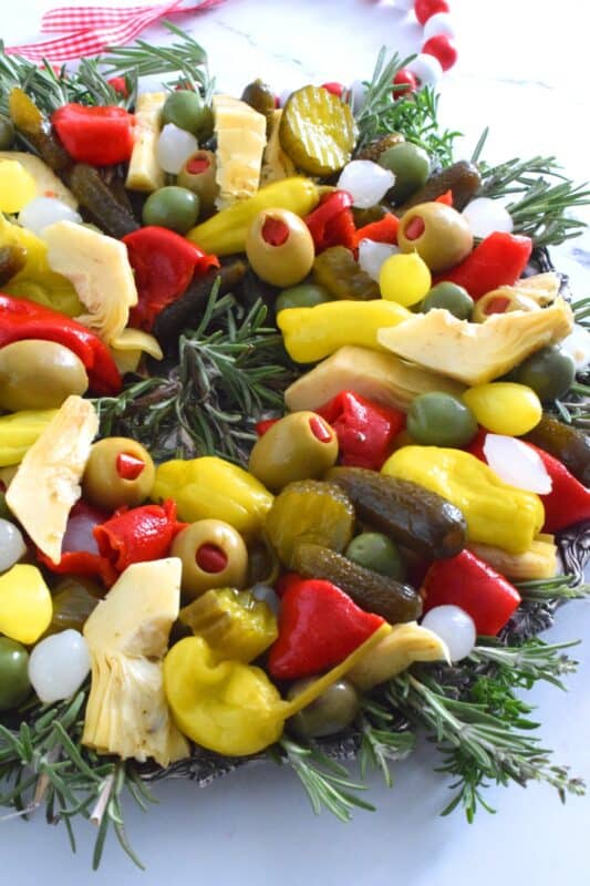 This bright and shiny edible wreath is packed full of sweet, salty, and tangy flavour! Consisting of your favourite pickled and marinated foods, an Olive and Pickle Wreath is the answer to every host's holiday appetizer table. Assemble on a platter and refrigerate until ready to serve. It's easy, delicious, and festive! #olives #pickles #charcuterie #christmas #holiday #partyfood