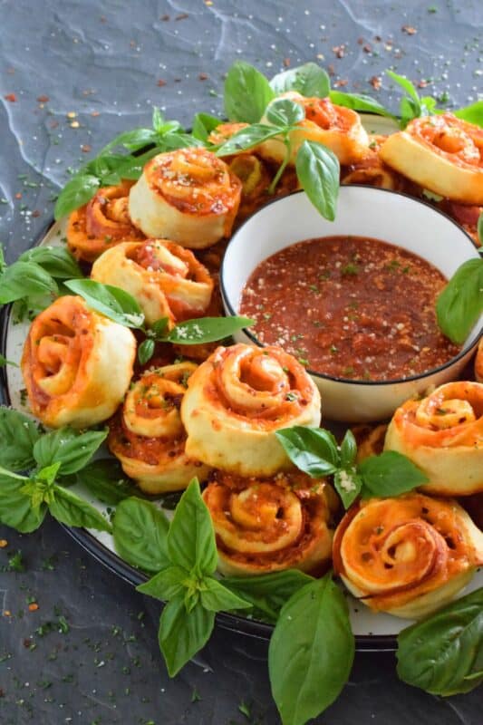 Whip up a batch of these Cheesy Pizza Roll Dippers quickly and easily with the help of store-bought, frozen pizza dough! Layer the dippers with lots of cheese, a quick and easy homemade pizza sauce, and toppings of your choice! These puff up in the oven and are brown and slightly crispy on the bottom with ooey-gooey cheese bubbling out of the top. Complete with a delicious marinara dip, who could resist? #pizza #pizzarolls #rollups #dip #dippers