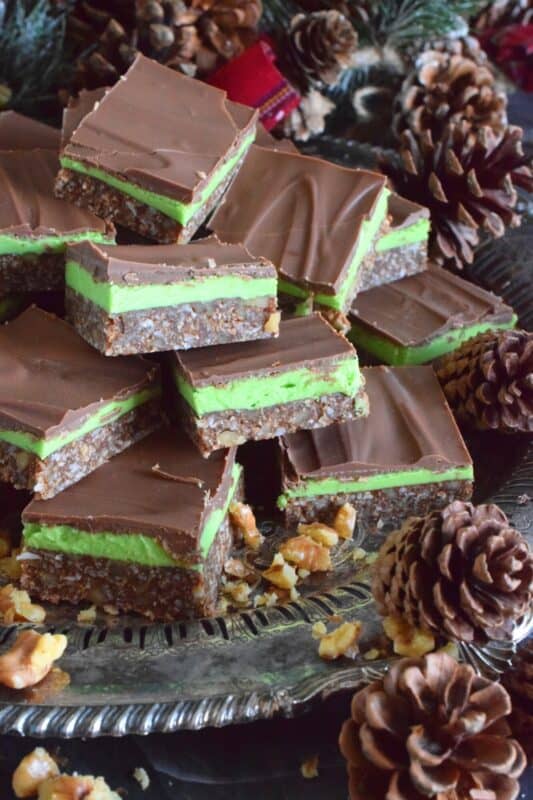 Triple-layered with wonderful flavours, these No Bake Mint Squares are perfectly festive for the holiday season.  With a coconut, walnut, and graham crumb base, and a creamy mint filling, these squares are topped with melted chocolate which makes them all the more rich and delicious.  You simply must add these to your Christmas cookie platter! #nanaimo #mint #peppermint #squares #bars #nobake