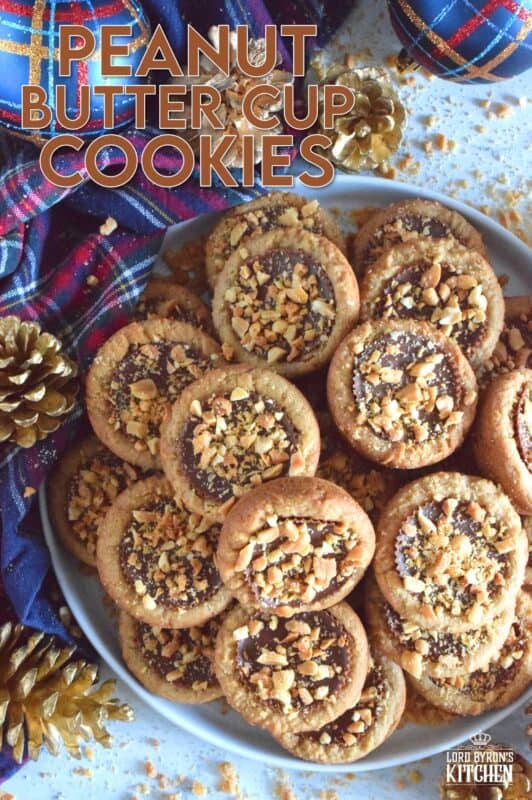 Thumbprint-style cookies are very popular at Christmastime, so why not over-stuff them with a full-sized Peanut Butter Cup?  These cookies are so easy to make and are baked in muffin tins!  Push in the peanut butter cup and top with chopped peanuts for more texture and flavour! #peanutbutter #reeses #cookies #thumbprint