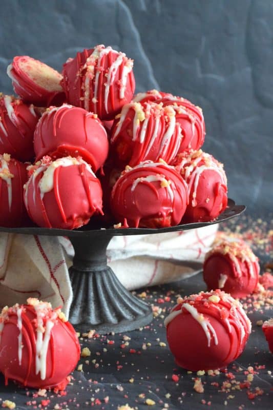 Prepared with crushed vanilla-flavoured Golden Oreos, cream cheese, and homemade strawberry shortcake crumbs, these Strawberry Shortcake Truffles are dipped in melted red candy melts and drizzled with white melted chocolate. They’re beautifully bold and bright, and delicious too! #truffles #valentines #nobake #pink #candy