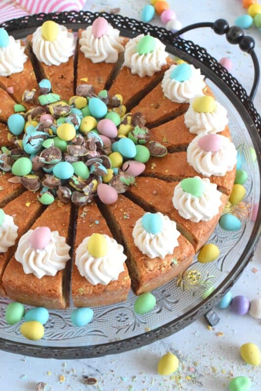 Prepared with crushed chocolate mini eggs and topped with a dollop of buttercream frosting, this Easter Mini Egg Tea Cake looks quite delicious and inviting! Keep the decorating simple with a pile of mini eggs right in the center and let the cake speak for itself!  A delightful treat, this cake is a beautiful Easter dessert! #minieggs #easter #cadbury #cake #teacake