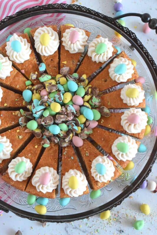 Prepared with crushed chocolate mini eggs and topped with a dollop of buttercream frosting, this Easter Mini Egg Tea Cake looks quite delicious and inviting! Keep the decorating simple with a pile of mini eggs right in the center and let the cake speak for itself!  A delightful treat, this cake is a beautiful Easter dessert! #minieggs #easter #cadbury #cake #teacake
