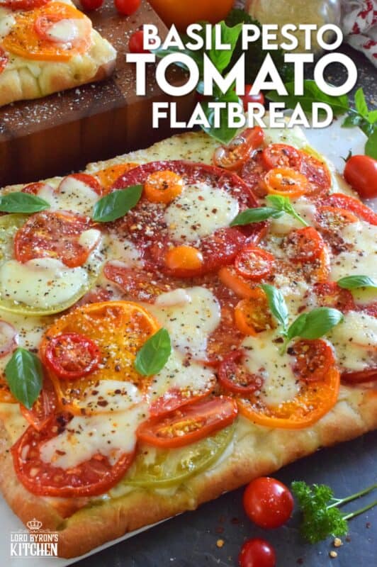 Freshly sliced tomatoes and cheese are piled onto a quick and easy homemade flatbread with the best double parmesan basil pesto sauce.  Baked to perfection and topped with fresh basil leaves and ground black pepper, this is a very scrumptiously delicious recipe! #tomatoes #flatbread #heirloom #summerfresh