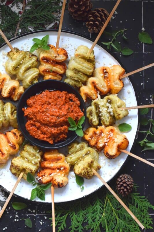 This light and airy appetizer is prepared with store-bought sheets of frozen puff pastry and your favourite sun-dried tomato or basil pesto.  They're so quick and easy to prepare - anyone can do this!  Serve with a side of warm marinara sauce for best results. #holilday #christmas #appetizer #puffpastry #pesto
