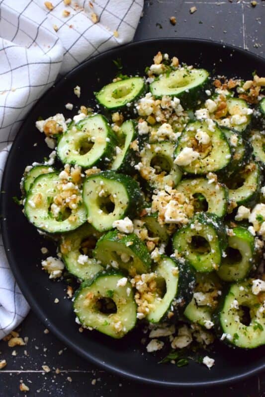 A great side or a refreshing snack, Sweet and Salty Cucumber Rings are the result of summer fresh cucumbers being paired with toasted pecans, crumbled feta, and lots of drizzled honey. Serve at room temperature immediately after preparing for the best results! #cucumber #sweetandsalty #salad #snack #feta