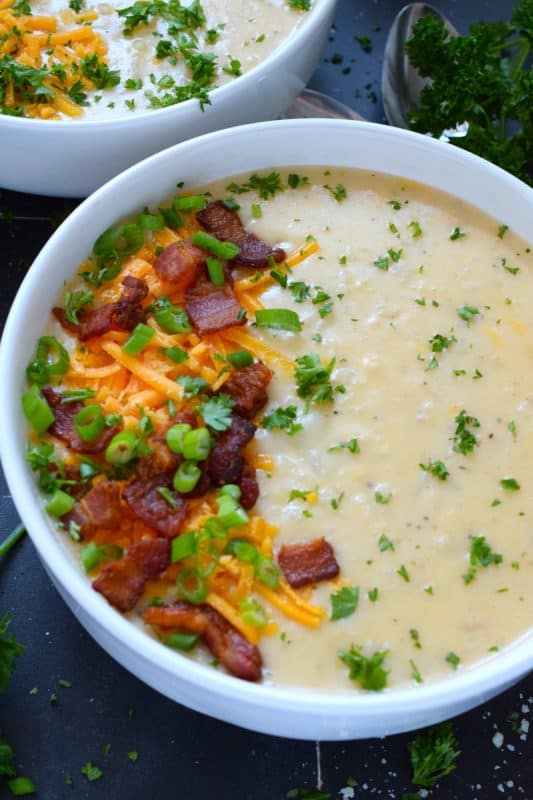 Creamy and smooth, this Baked Potato Soup is prepared with onion and garlic in a simple roux which is what makes the soup thick and lucious. Add cheese and crumbled cooked bacon for even more texture and flavour! Serve with warm, crusty bread for a complete, hearty meal! #bakedpotato #creamy #soup #cheesy #potatoes