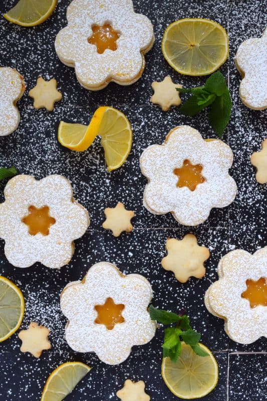 This recipe starts with an easy to prepare shortbread cookie that is generously infused with freshly grated lemon zest.  Once baked and cooled, two cookies are sandwiched with lemon curd; these Lemon Sandwich Cookies are super refreshing and make a perfect summertime treat or springtime brunch dessert! #lemon #curd #zest #sandwich #cookies