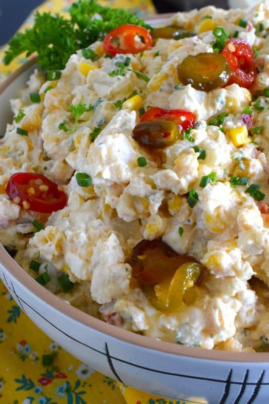 Chopped potatoes are tossed with sweet corn, spicy jalapenos, boiled eggs, fresh green and red onions, and salty cotija cheese to create this most delicious Mexican Street Corn Potato Salad! With its creamy, zingy, and tart dressing, this potato salad will most definitely be the most popular side at any backyard barbecue this summer! #salad #potato #streetcorn #mexican #cotija