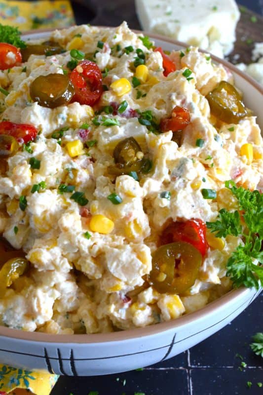Chopped potatoes are tossed with sweet corn, spicy jalapenos, boiled eggs, fresh green and red onions, and salty cotija cheese to create this most delicious Mexican Street Corn Potato Salad! With its creamy, zingy, and tart dressing, this potato salad will most definitely be the most popular side at any backyard barbecue this summer! #salad #potato #streetcorn #mexican #cotija