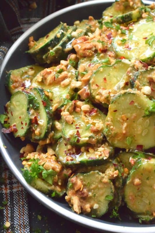 Fresh cucumbers are sliced and tossed in a quick and easy homemade nutty, salty, creamy, spicy, and garlicky sauce.  Toasting the peanuts first and combining them with peanut butter, soy sauce, and rice vinegar makes a delicious cold side, salad, or snack.  Serve at room temperature immediately after preparing for the best results! #cucumber #peanut #peanutbutter #peanutsauce #salad #spicy