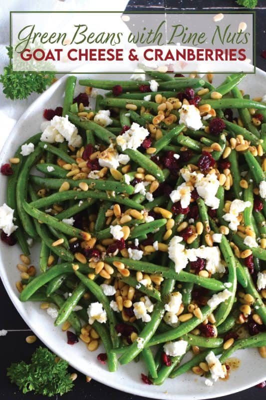 This delicious side dish prepared with green beans, toasted pine nuts, crumbled goat cheese, and dried cranberries takes only fifteen minutes in a skillet on your stovetop! How's that for a quick and easy holiday side?  Perfectly seasoned and quickly sauteed in butter, these green beans are delectably savoury! #greenbeans #cheese #pinenuts #thanksgiving #side