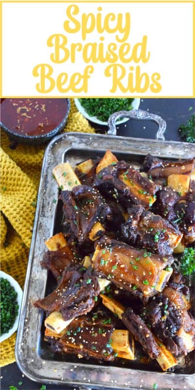 Beef ribs are braised in a sweet and sticky sauce prepared with red pepper paste and chilies. These moist and tender ribs are perfect for a cold winter night’s dinner!  Using easy to find Asian ingredients, these Spicy Braised Beef Ribs are easy to prepare and are simmered until the meat is practically falling off the bone! #beef #beefribs #spicy #braised