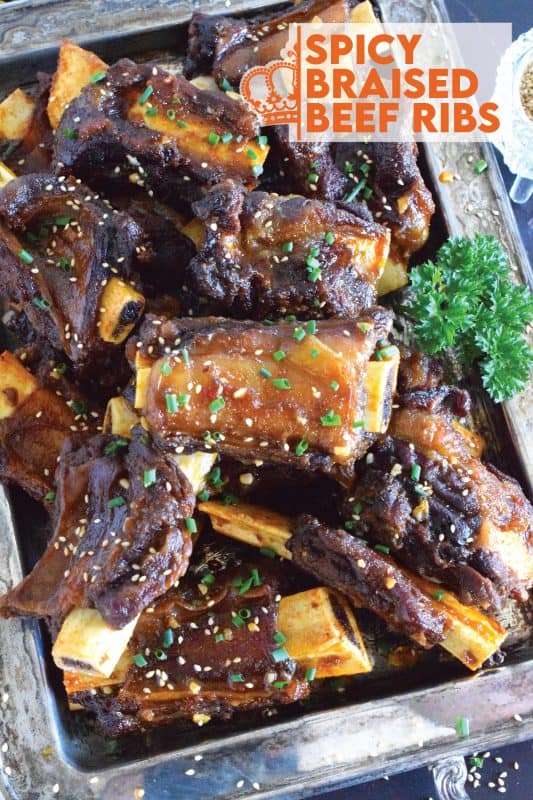 Beef ribs are braised in a sweet and sticky sauce prepared with red pepper paste and chilies. These moist and tender ribs are perfect for a cold winter night’s dinner!  Using easy to find Asian ingredients, these Spicy Braised Beef Ribs are easy to prepare and are simmered until the meat is practically falling off the bone! #beef #beefribs #spicy #braised