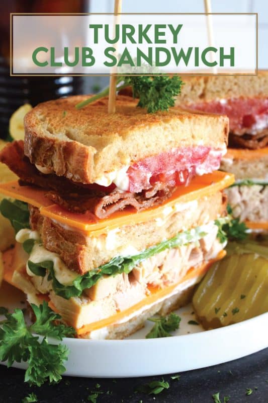 A classic restaurant-style club sandwich will never go out of style! Easily prepare these Turkey Club Sandwiches at home with leftover holiday turkey, crispy bacon slices, fresh lettuce and tomato, a good smear of mayonnaise, and some sliced sharp cheddar cheese! Everything is piled onto toasted sandwich bread and served with a side of potato chips and a pickle.  You can't beat it! #turkey #club #leftover #sandwich #clubsandwich #bacon
